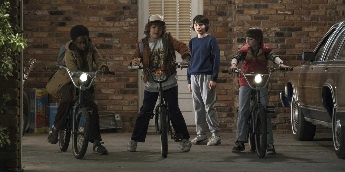 Troje dzieci na rowerach otacza chłopca w niebieskiej bluzie: kto jest główną postacią Stranger Things?
